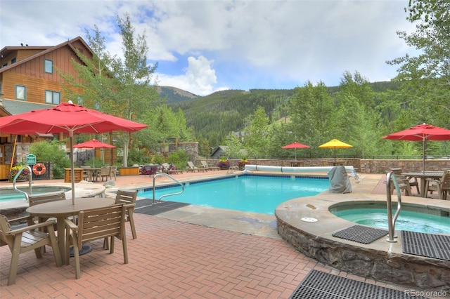 view of pool with an in ground hot tub, a mountain view, and a patio