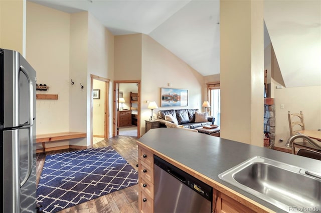 kitchen with appliances with stainless steel finishes, sink, dark wood-type flooring, and high vaulted ceiling