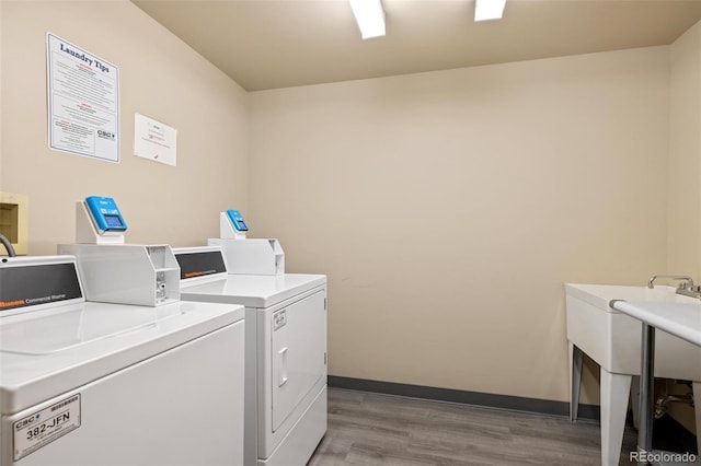 laundry room with washing machine and dryer and light wood-type flooring
