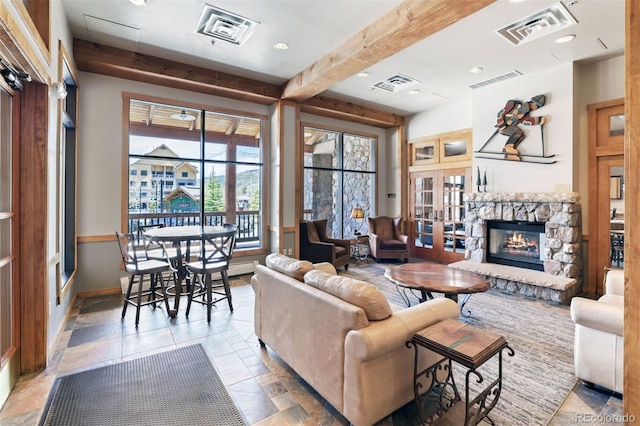 living room with beam ceiling, a stone fireplace, and french doors