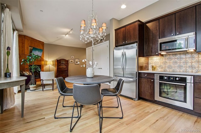 340 S Lafayette St Unit 204, Denver, CO 80209 - kitchen featuring stainless steel appliances, light wood finished floors, a chandelier, and dark brown cabinetry