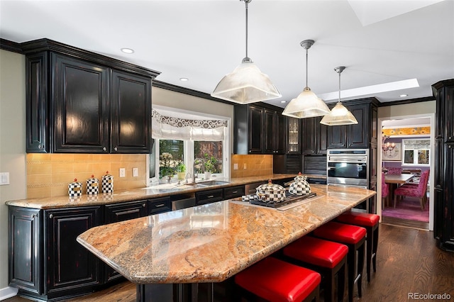 kitchen with pendant lighting, sink, stainless steel appliances, dark hardwood / wood-style floors, and a center island