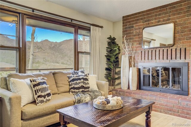 9610 Mohawk Trl, Cascade, CO 80809 - living room with wood finished floors, a brick fireplace, a mountain view, and a textured ceiling