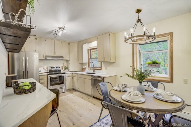 9610 Mohawk Trl, Cascade, CO 80809 - kitchen with stainless steel appliances, a chandelier, under cabinet range hood, cream cabinetry, and a sink