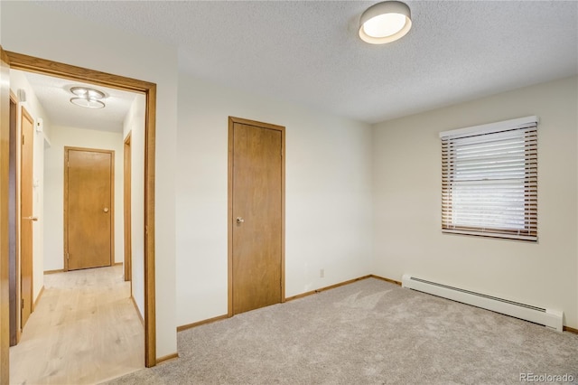 9610 Mohawk Trl, Cascade, CO 80809 - unfurnished bedroom with baseboard heating, a textured ceiling, baseboards, a closet, and light colored carpet