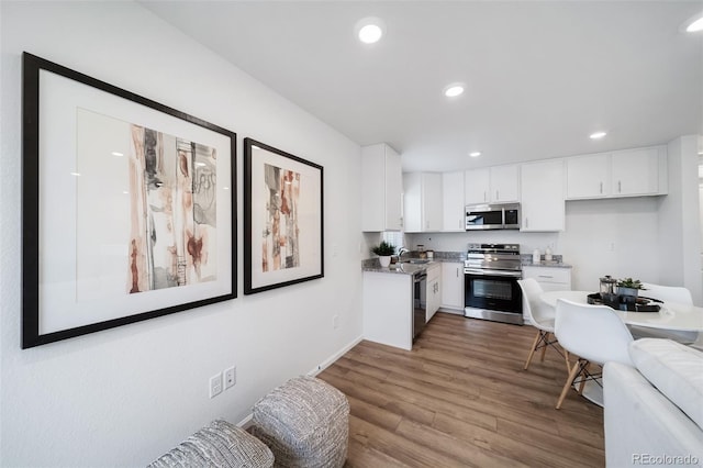 46546 Avery Ln, Bennett, CO 80102 - kitchen with appliances with stainless steel finishes, white cabinetry, wood finished floors, a sink, and recessed lighting