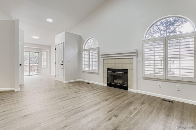 8346 S Upham Way, Littleton, CO 80128 - unfurnished living room featuring healthy amount of natural light, wood finished floors, a tile fireplace, and vaulted ceiling