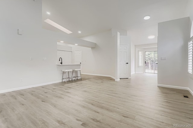 8346 S Upham Way, Littleton, CO 80128 - unfurnished living room featuring light wood finished floors, a skylight, and recessed lighting