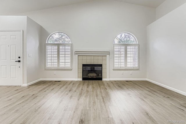 8346 S Upham Way, Littleton, CO 80128 - unfurnished living room with wood finished floors, healthy amount of natural light, a tile fireplace, and high vaulted ceiling