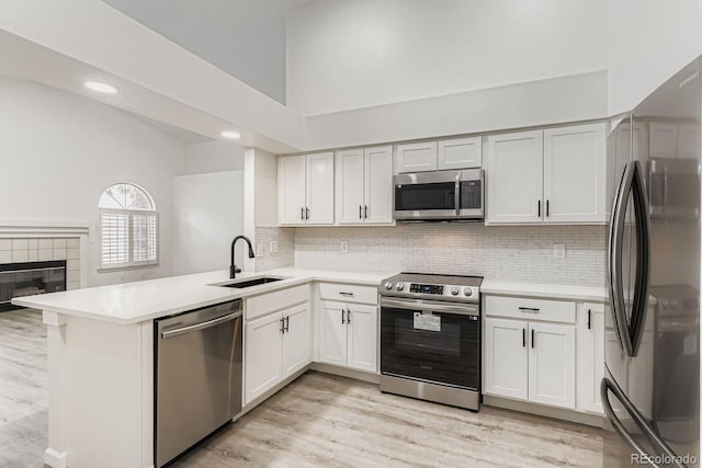 8346 S Upham Way, Littleton, CO 80128 - kitchen featuring stainless steel appliances, light countertops, a peninsula, tasteful backsplash, and light wood-style flooring