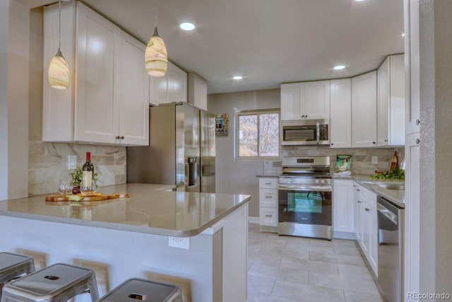 kitchen featuring a breakfast bar, white cabinets, decorative light fixtures, kitchen peninsula, and stainless steel appliances