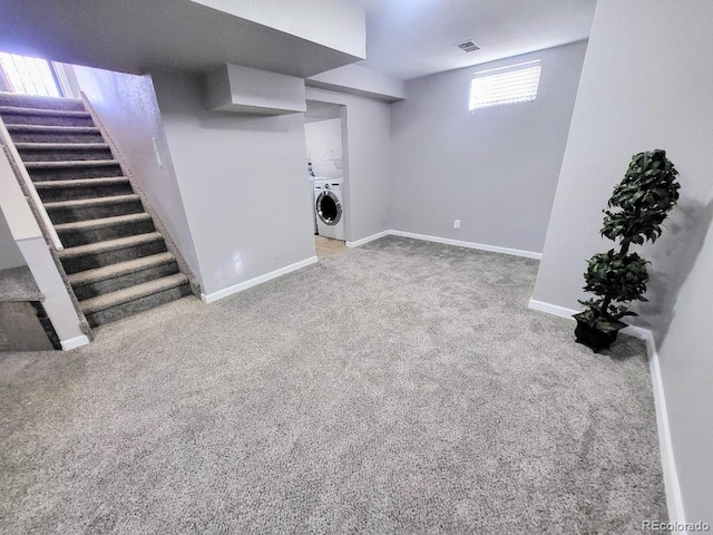 basement featuring independent washer and dryer, light colored carpet, and plenty of natural light