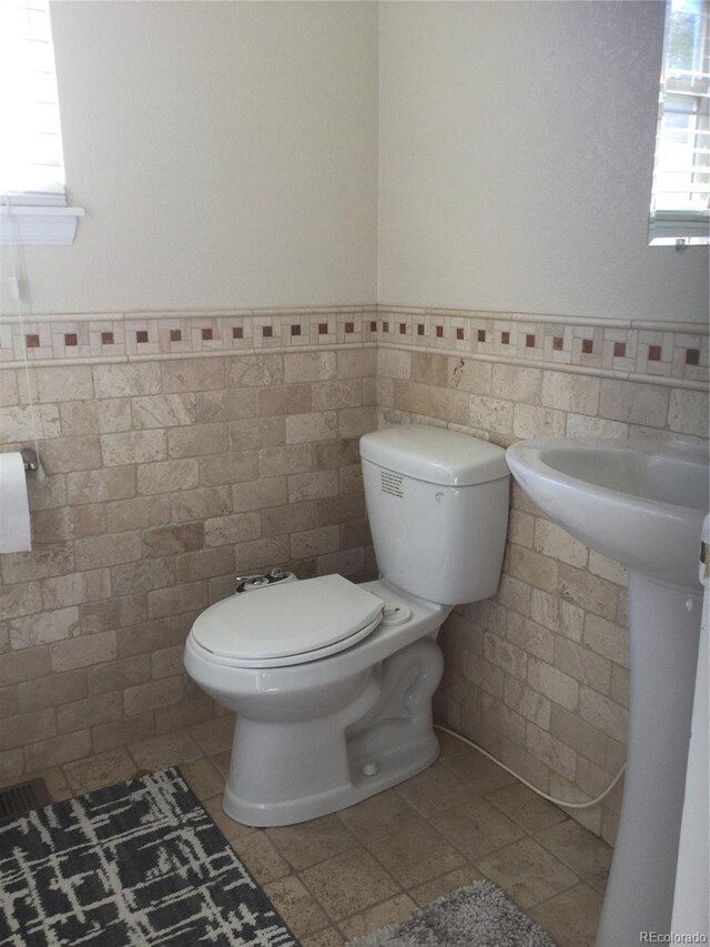 13674 Plaster Cir, Broomfield, CO 80023 - bathroom featuring tile walls, toilet, and a wainscoted wall