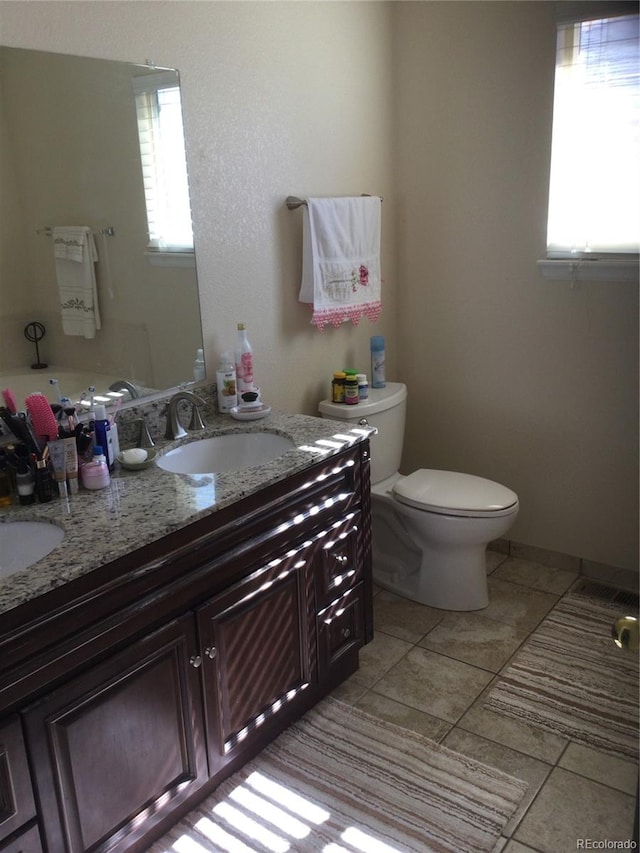 bathroom featuring vanity, toilet, a healthy amount of sunlight, and tile patterned flooring