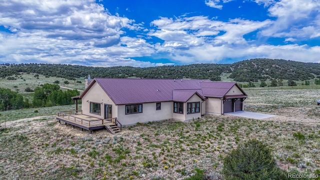 1610 Timber Ridge Rd, Westcliffe, CO 81252 - view of front of home featuring stucco siding, a metal roof, an attached garage, a chimney, and a deck with mountain view