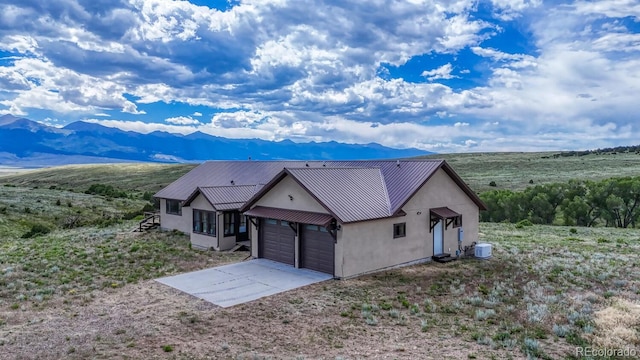 1610 Timber Ridge Rd, Westcliffe, CO 81252 - view of front of home with stucco siding, a garage, a metal roof, driveway, and a mountain view