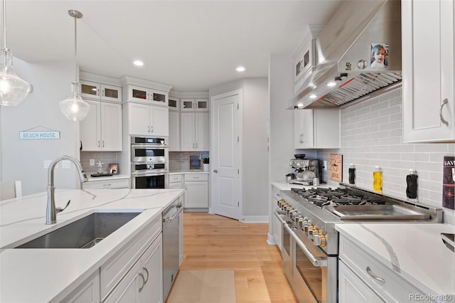 6614 S Vandriver Way, Aurora, CO 80016 - kitchen with range hood, appliances with stainless steel finishes, backsplash, white cabinets, and recessed lighting