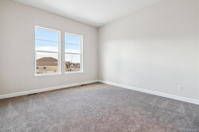 unfurnished room with carpet, visible vents, and baseboards