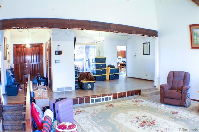 living room with an inviting chandelier, baseboards, visible vents, and wood finished floors