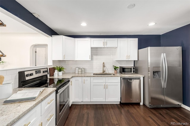 6390 W 45th Ave, Wheat Ridge, CO 80033 - kitchen with stainless steel appliances, backsplash, dark wood-style floors, white cabinetry, and light stone countertops