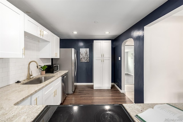 6390 W 45th Ave, Wheat Ridge, CO 80033 - kitchen featuring appliances with stainless steel finishes, arched walkways, white cabinets, decorative backsplash, and dark wood-type flooring