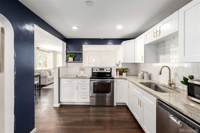 6390 W 45th Ave, Wheat Ridge, CO 80033 - kitchen featuring stainless steel appliances, arched walkways, light stone counters, tasteful backsplash, and recessed lighting