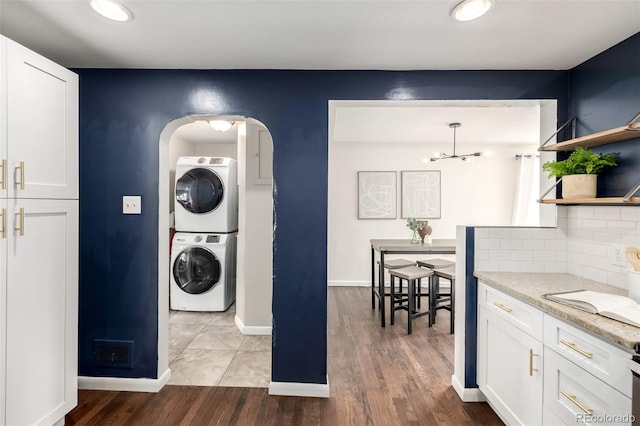 6390 W 45th Ave, Wheat Ridge, CO 80033 - laundry area featuring stacked washer and clothes dryer, arched walkways, light wood-style floors, and recessed lighting