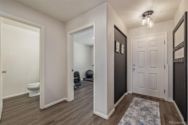 entryway with dark wood finished floors and baseboards