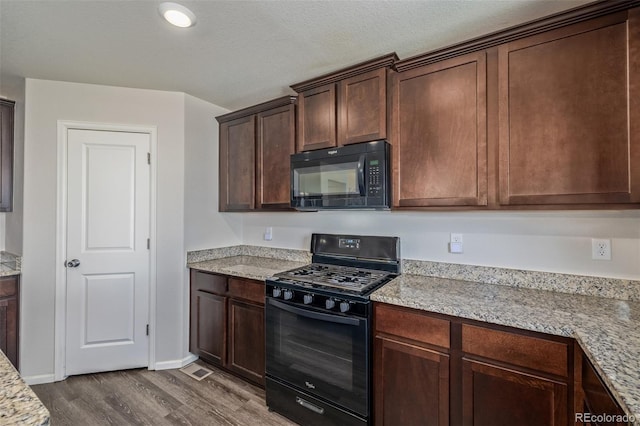 kitchen featuring dark brown cabinets, baseboards, black appliances, light stone counters, and dark wood-style floors