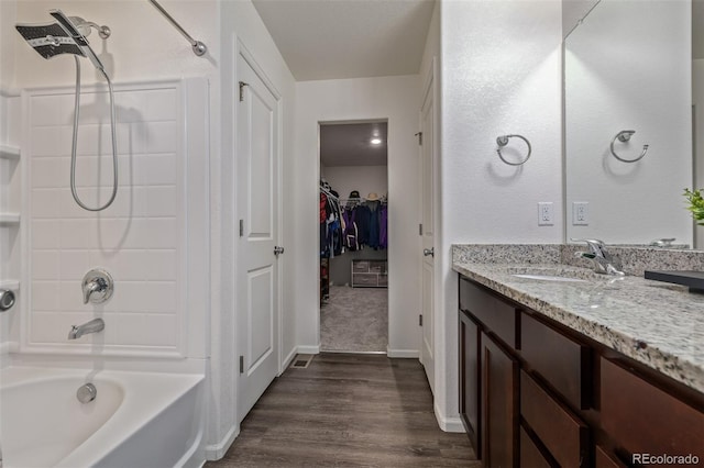 bathroom featuring shower / washtub combination, wood finished floors, vanity, a walk in closet, and baseboards