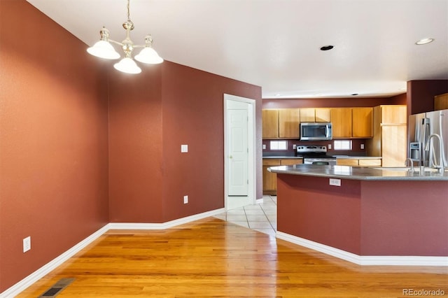 kitchen with sink, stainless steel appliances, a notable chandelier, and light hardwood / wood-style floors