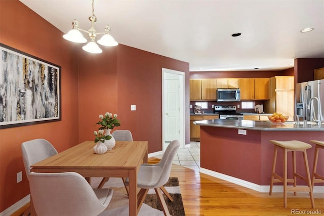 dining area with light wood-type flooring and a notable chandelier