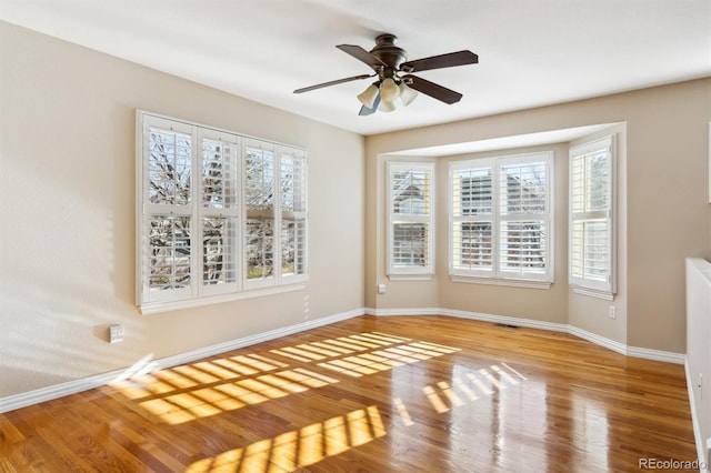 spare room featuring hardwood / wood-style flooring, ceiling fan, and a healthy amount of sunlight