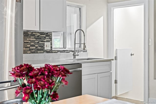 kitchen featuring white cabinets, decorative backsplash, stainless steel appliances, and sink