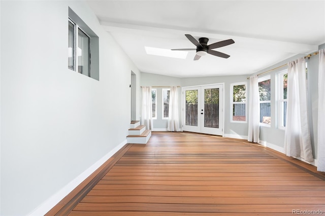 unfurnished sunroom featuring ceiling fan, french doors, and vaulted ceiling with skylight