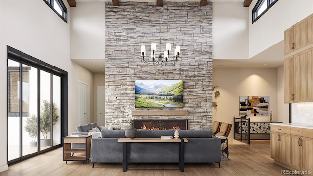 living room featuring a towering ceiling, a fireplace, beam ceiling, an inviting chandelier, and light hardwood / wood-style flooring