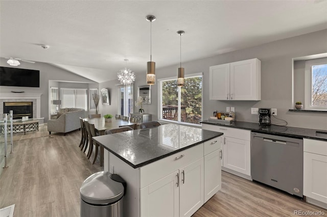 2970 Leoti Dr, Colorado Springs, CO 80922 - kitchen featuring dishwasher, plenty of natural light, light wood finished floors, a glass covered fireplace, and vaulted ceiling