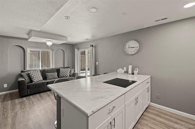 2970 Leoti Dr, Colorado Springs, CO 80922 - kitchen featuring black electric cooktop, a peninsula, white cabinets, light wood finished floors, and baseboards