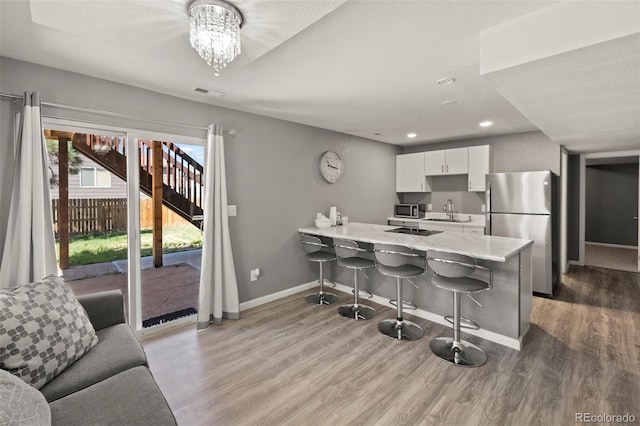2970 Leoti Dr, Colorado Springs, CO 80922 - kitchen featuring stainless steel appliances, a sink, a kitchen bar, baseboards, and wood finished floors