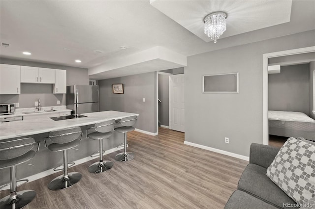 2970 Leoti Dr, Colorado Springs, CO 80922 - kitchen with a sink, baseboards, a breakfast bar, white cabinetry, and recessed lighting