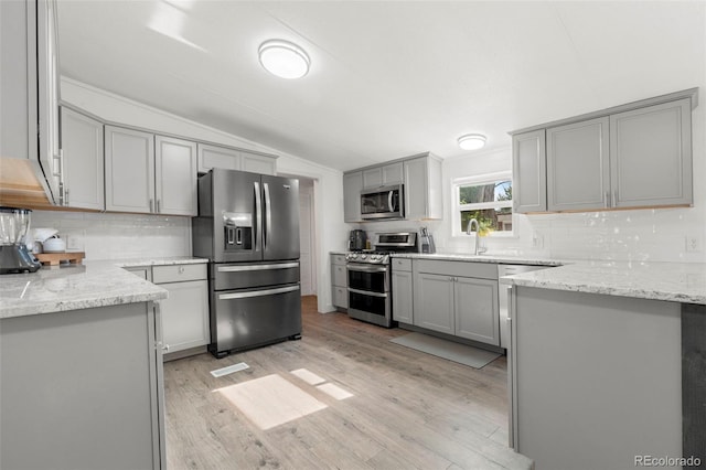 811 Plum Ave N, Lochbuie, CO 80603 - kitchen with stainless steel appliances, gray cabinets, lofted ceiling, decorative backsplash, and light wood-style floors