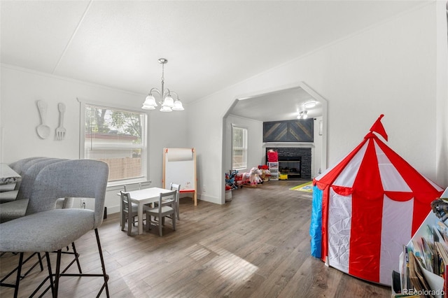 811 Plum Ave N, Lochbuie, CO 80603 - rec room with wood finished floors, a glass covered fireplace, a chandelier, and arched walkways
