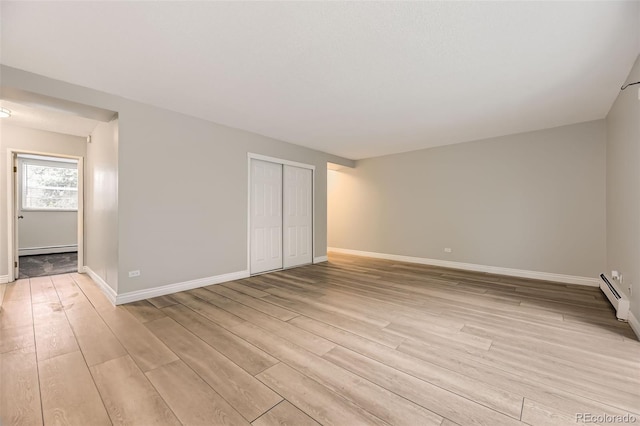 2160 S Vaughn Way Unit 104C, Aurora, CO 80014 - empty room featuring baseboards, a baseboard radiator, and light wood-style flooring