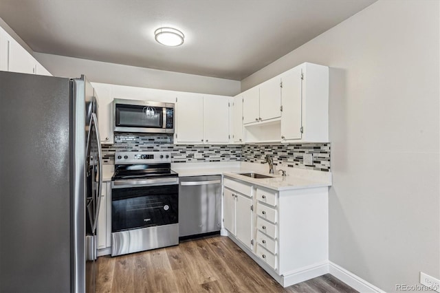 kitchen featuring backsplash, stainless steel appliances, wood-type flooring, sink, and white cabinets