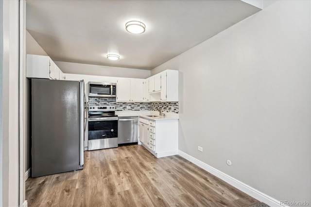 kitchen with white cabinetry, tasteful backsplash, light hardwood / wood-style flooring, sink, and appliances with stainless steel finishes