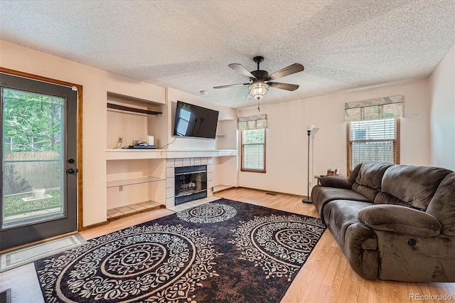5362 S Danube Ct, Centennial, CO 80015 - living room with light wood-type flooring, a ceiling fan, a fireplace, a textured ceiling, and built in features