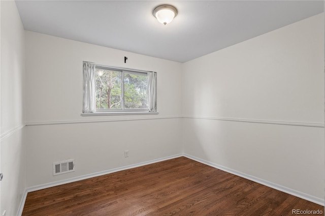 empty room with baseboards, visible vents, and wood finished floors