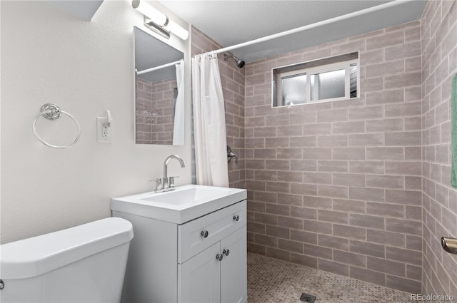 bathroom with vanity, toilet, and tiled shower