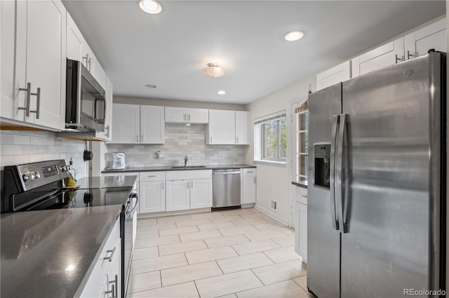 3117 Victor St, Aurora, CO 80011 - kitchen featuring appliances with stainless steel finishes, a sink, dark countertops, decorative backsplash, and white cabinetry