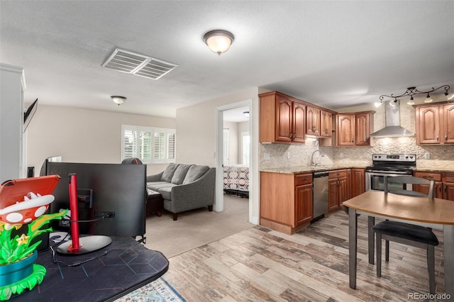 kitchen with visible vents, appliances with stainless steel finishes, wall chimney exhaust hood, and decorative backsplash